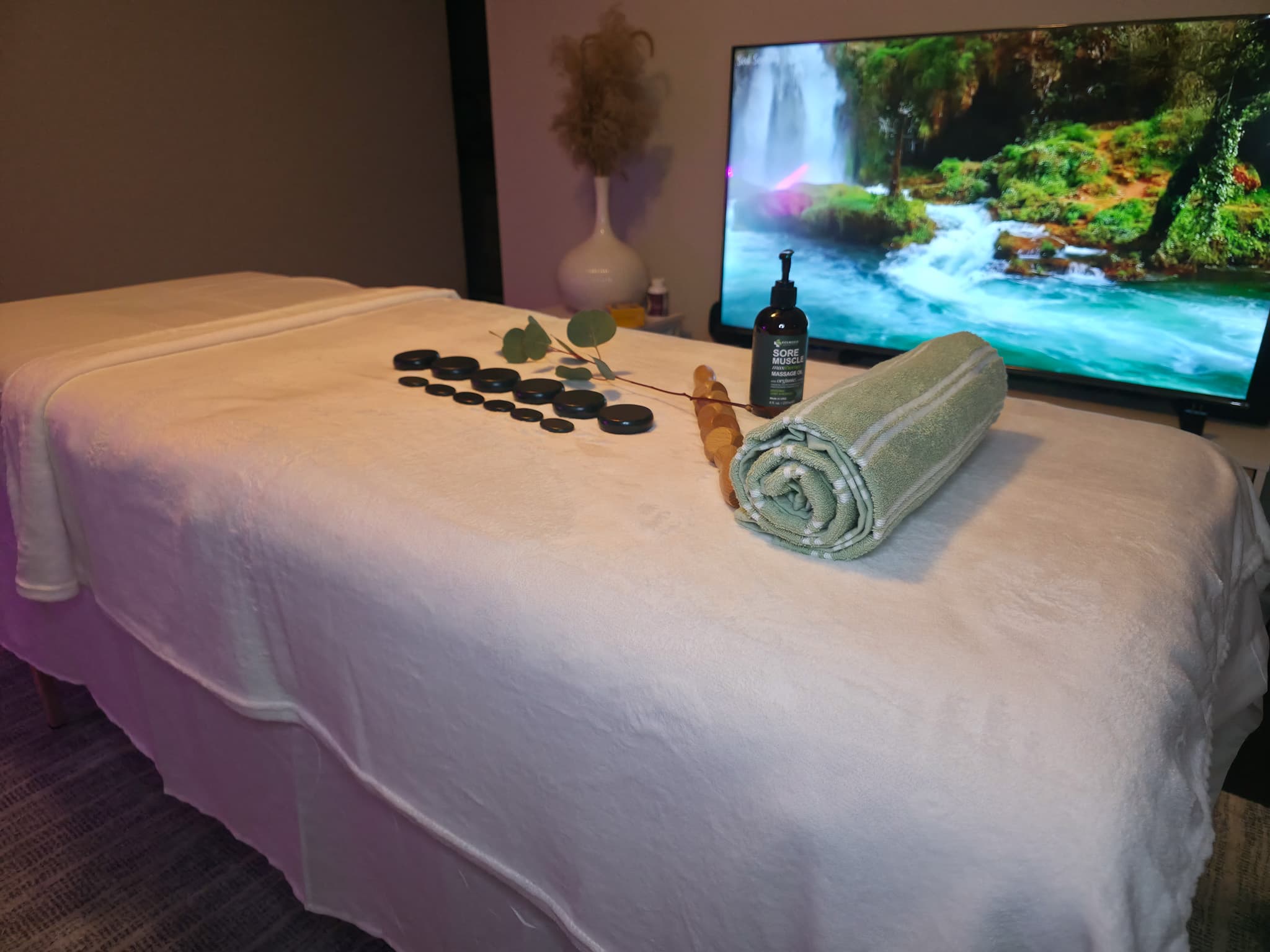 Massage table prepared with stones, towels, and massage oil for a mobile massage session.